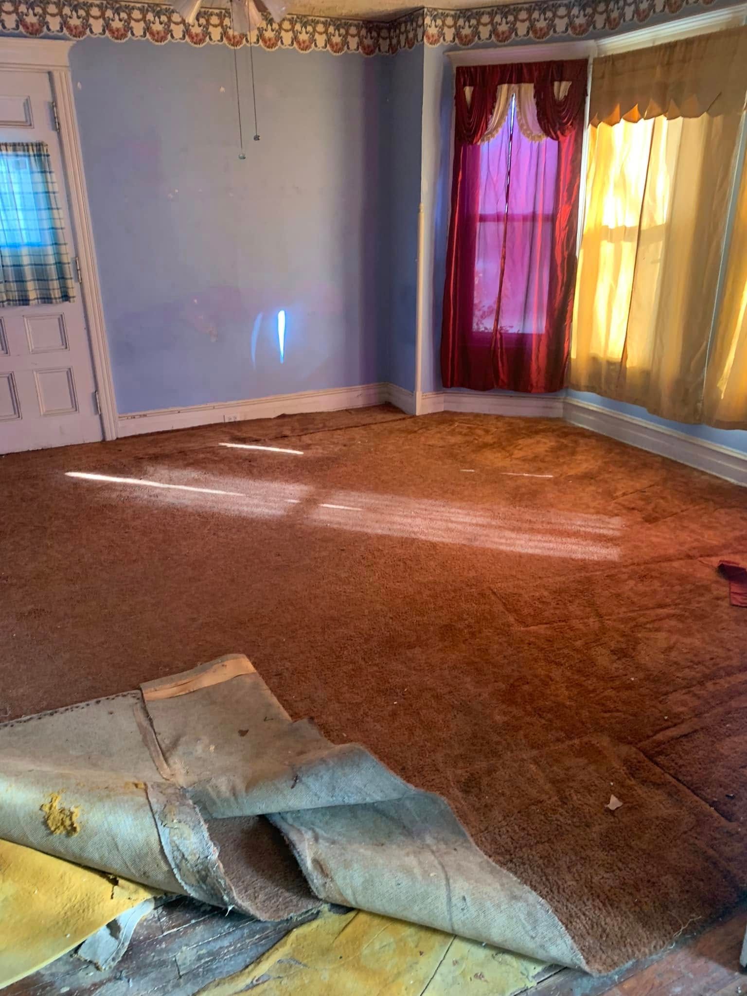 An empty living room with a carpeted floor and a window.
