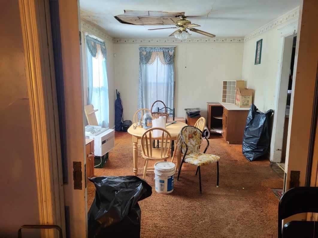 A living room with a table and chairs and a ceiling fan.