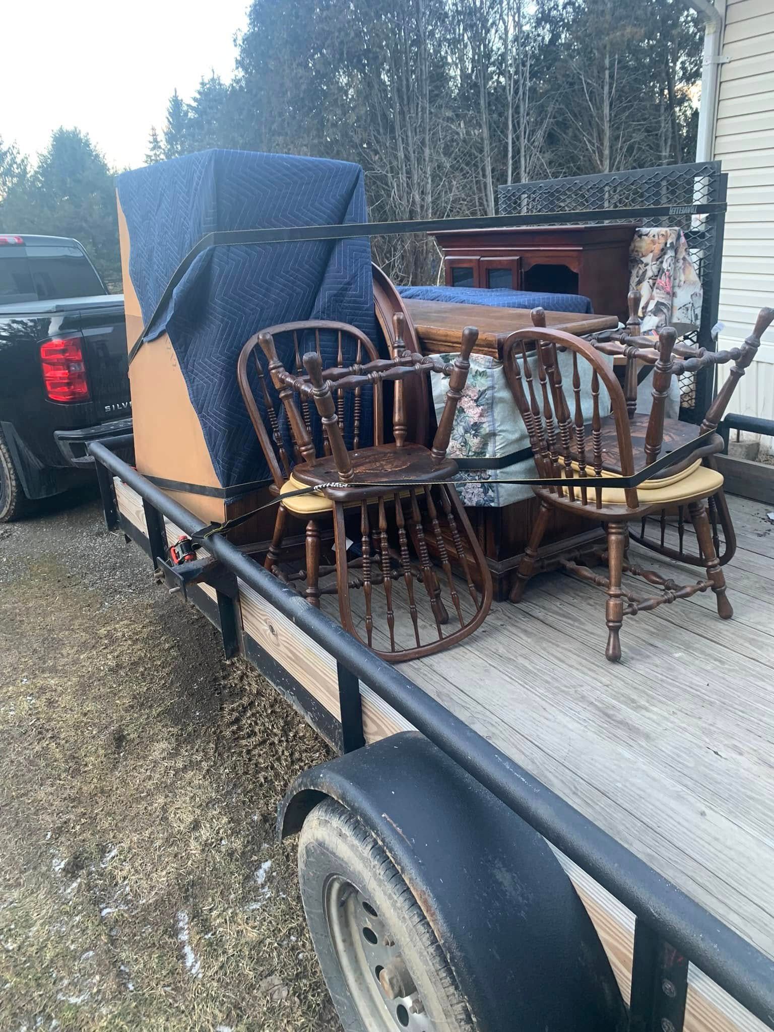 A trailer with a table and chairs on it is being pulled by a truck.