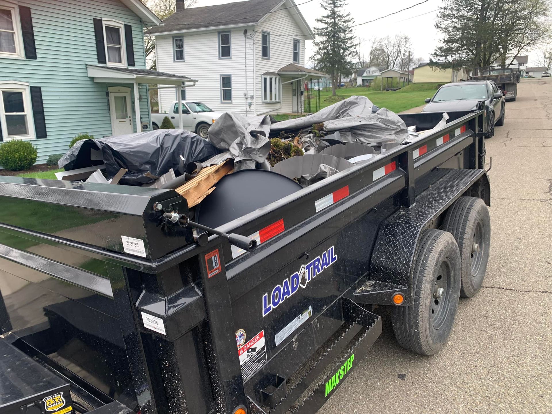 A dump truck is parked on the side of the road in front of a house.