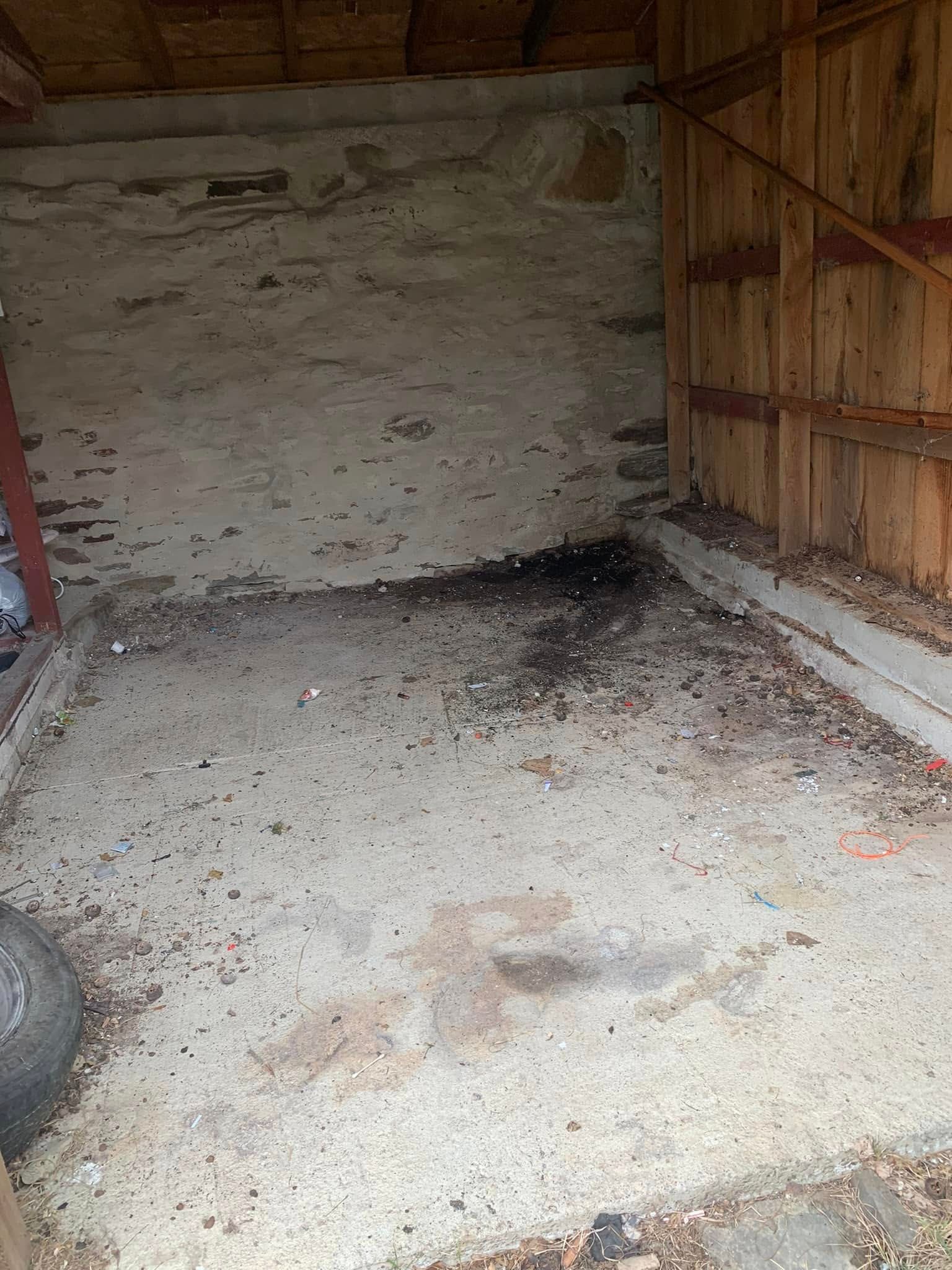 An empty room with a lot of dirt on the floor and a wooden wall.