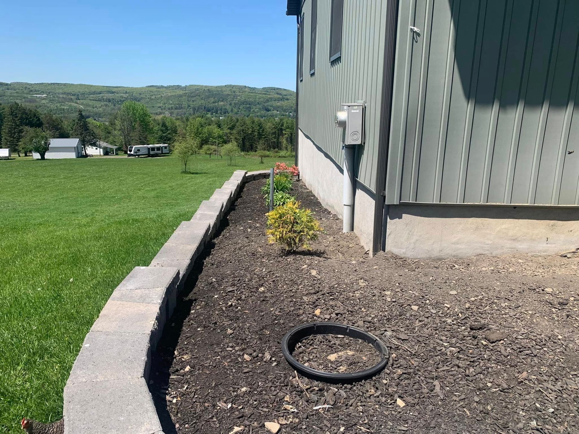 A house with a garden in front of it and a tire in the dirt.