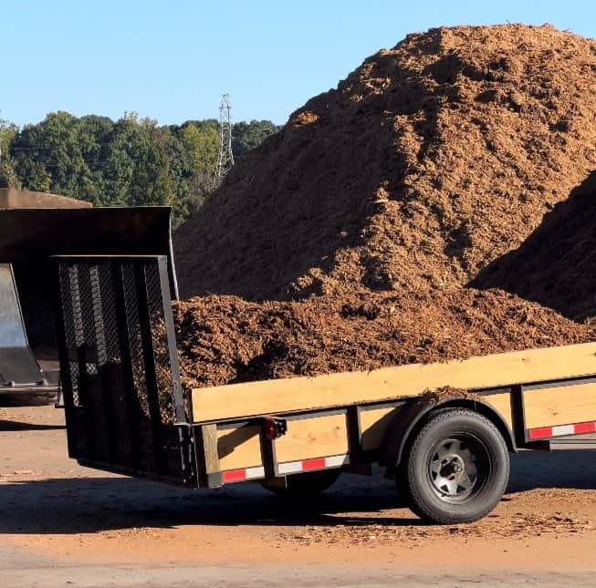 A trailer with a large pile of dirt behind it