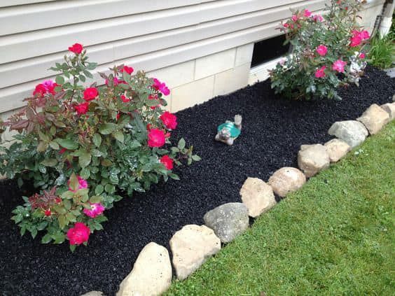 A garden with flowers and rocks in front of a house
