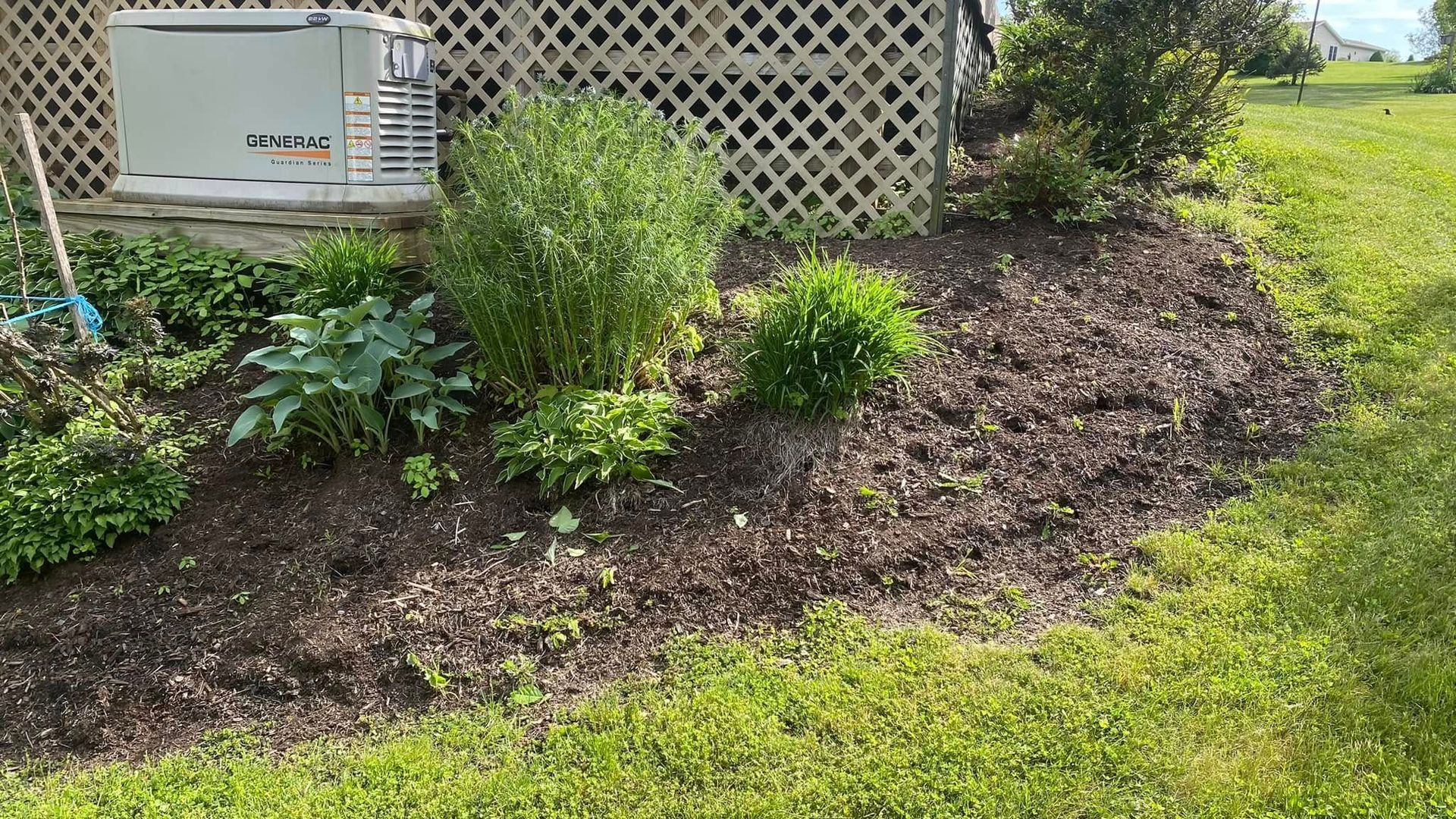 A generator is sitting in the grass next to a fence.