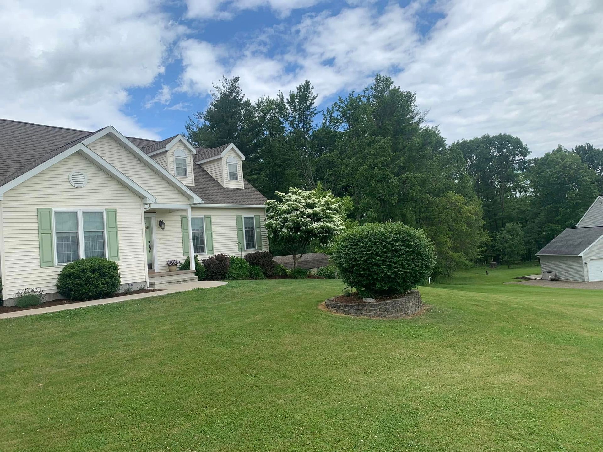 A white house with a large lawn in front of it.
