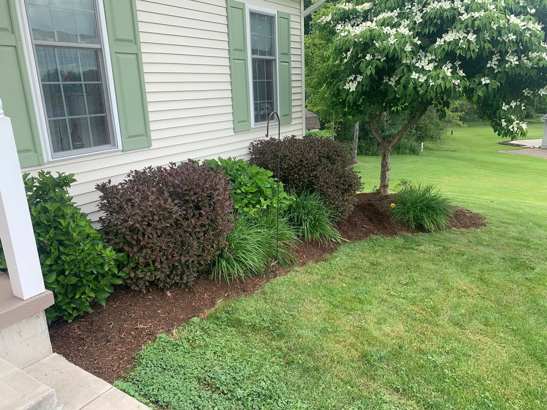 A house with green shutters and a lush green lawn