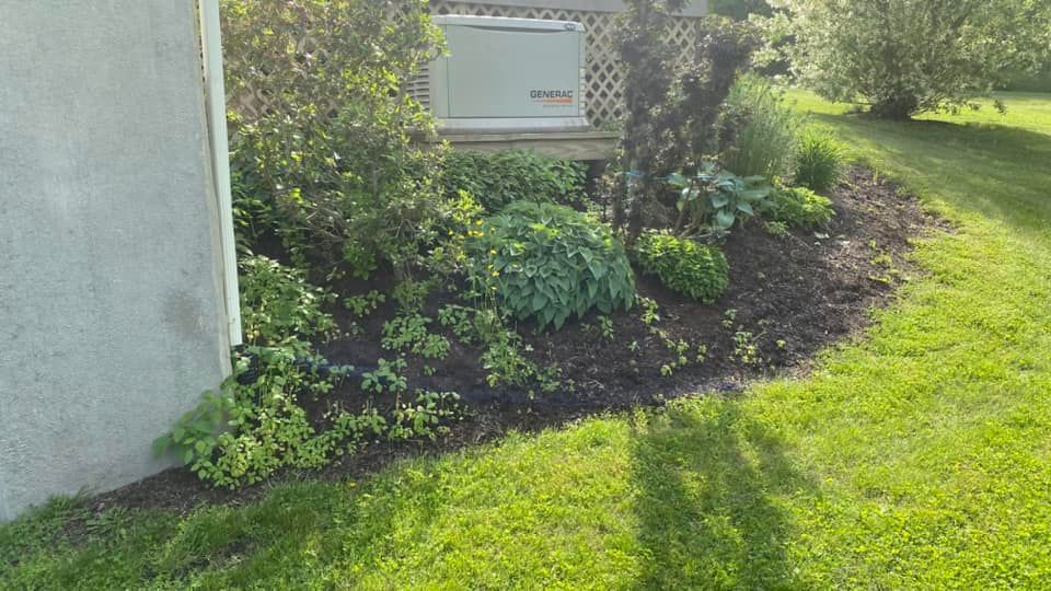 A generator is sitting in the grass next to a house.