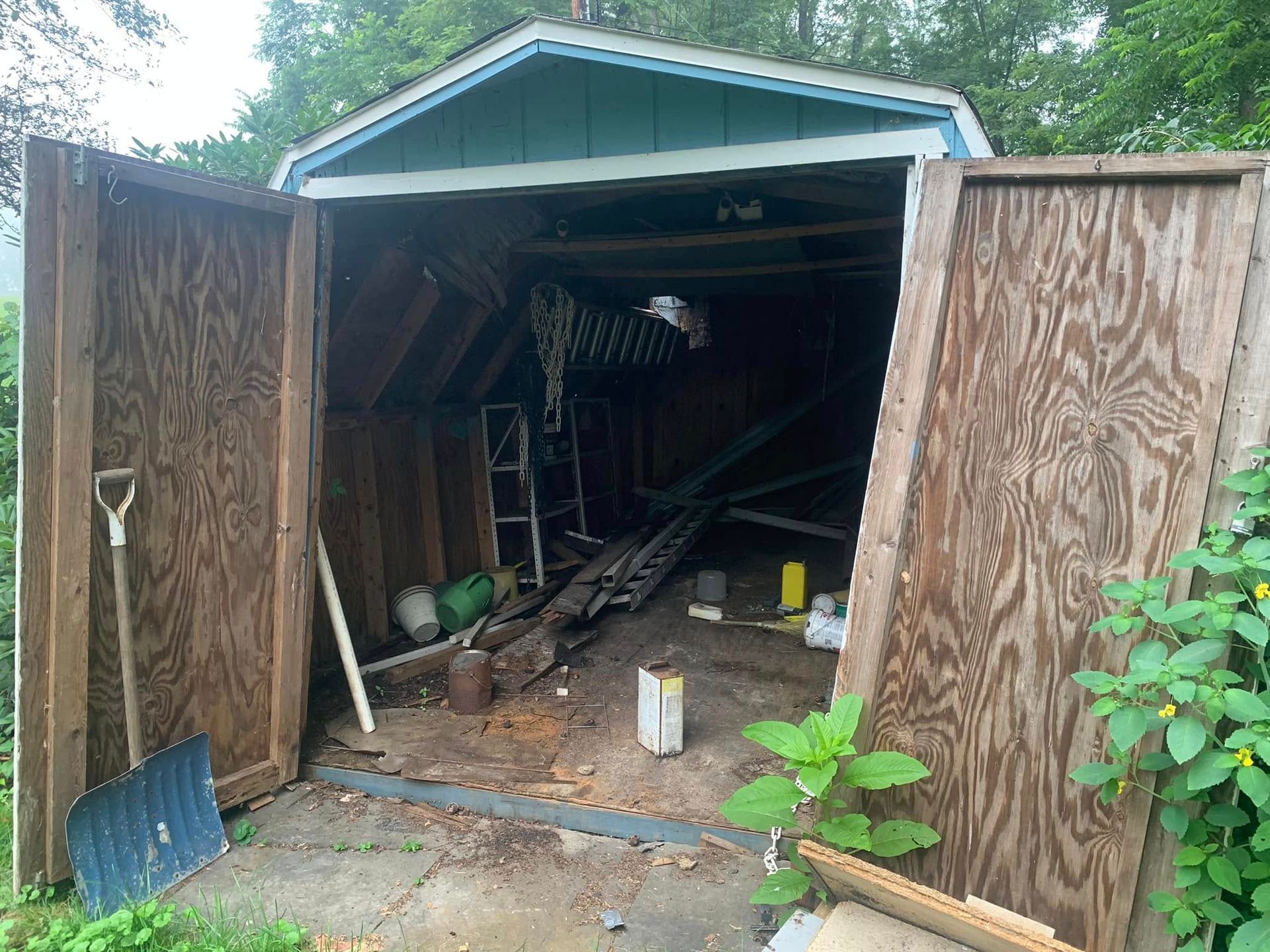 A garage with the doors open and a shovel in it