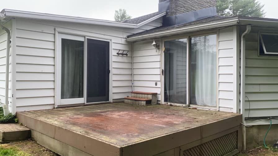 A white house with a concrete deck in front of it.