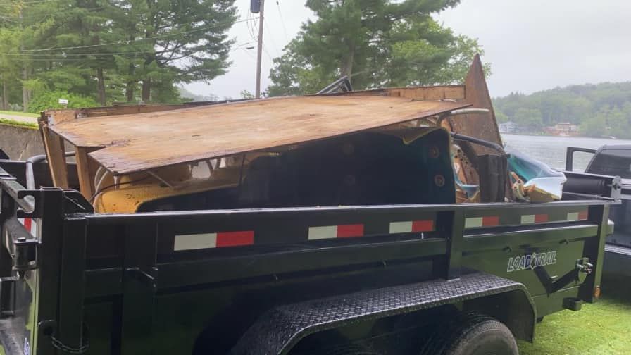 A dumpster with a wooden roof is sitting on top of a trailer.