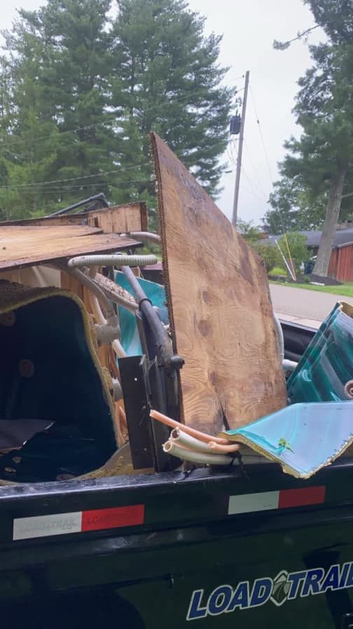 A dumpster with a lot of junk in it is parked on the side of the road.