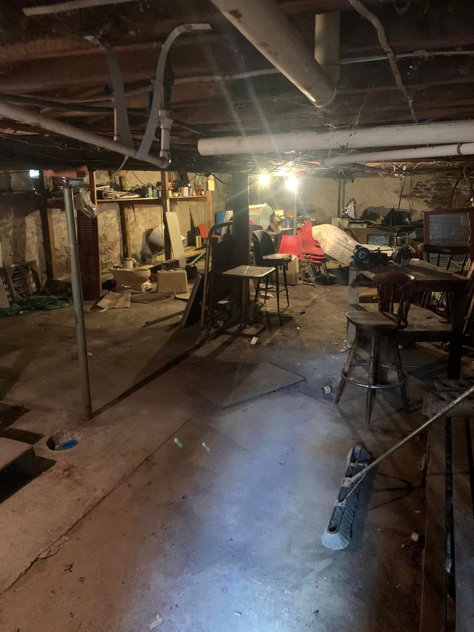 A basement with a lot of furniture and a light on the ceiling.