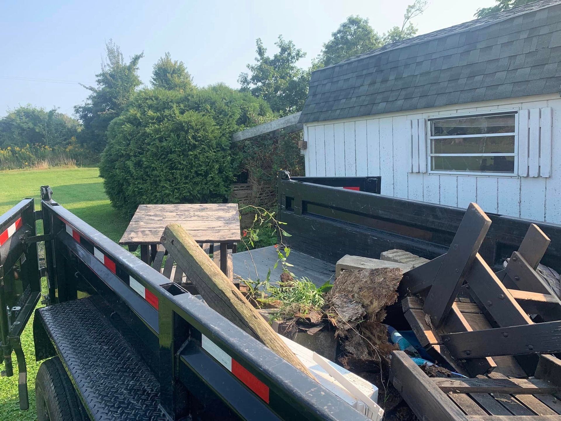 A trailer is sitting in front of a white house.