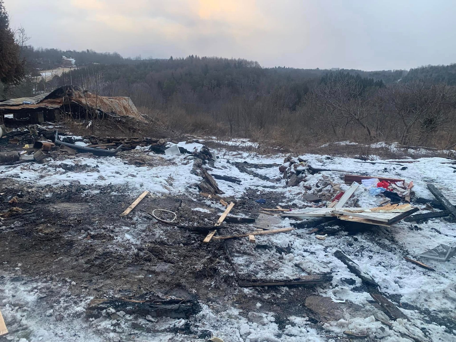 A large pile of wood is sitting in the middle of a snowy field.