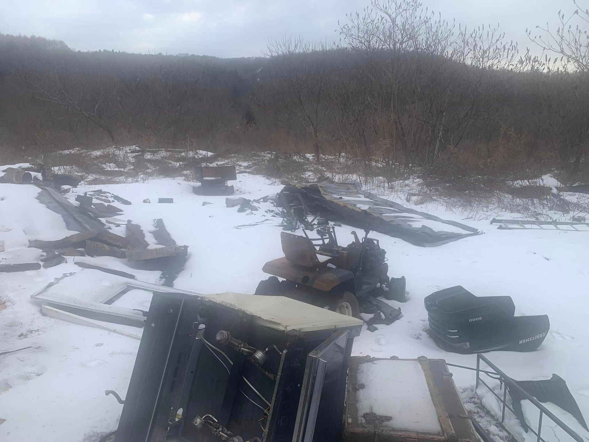 A pile of junk in the snow with a mountain in the background.