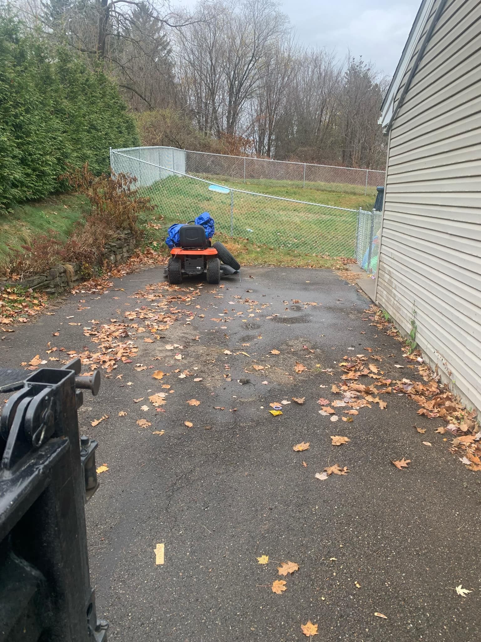 A lawn mower is parked in a driveway next to a house.