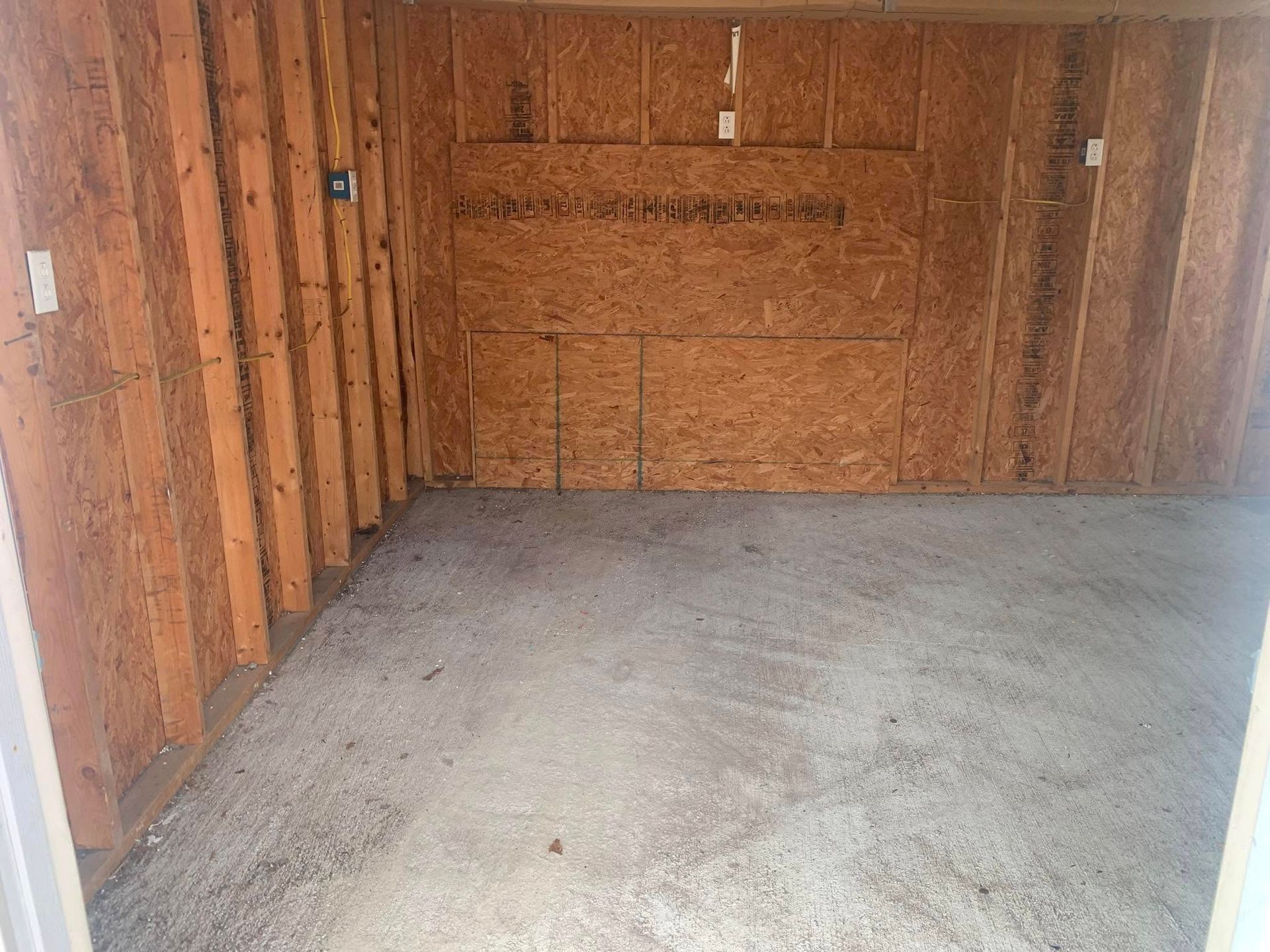 An empty room with a concrete floor and wooden walls.