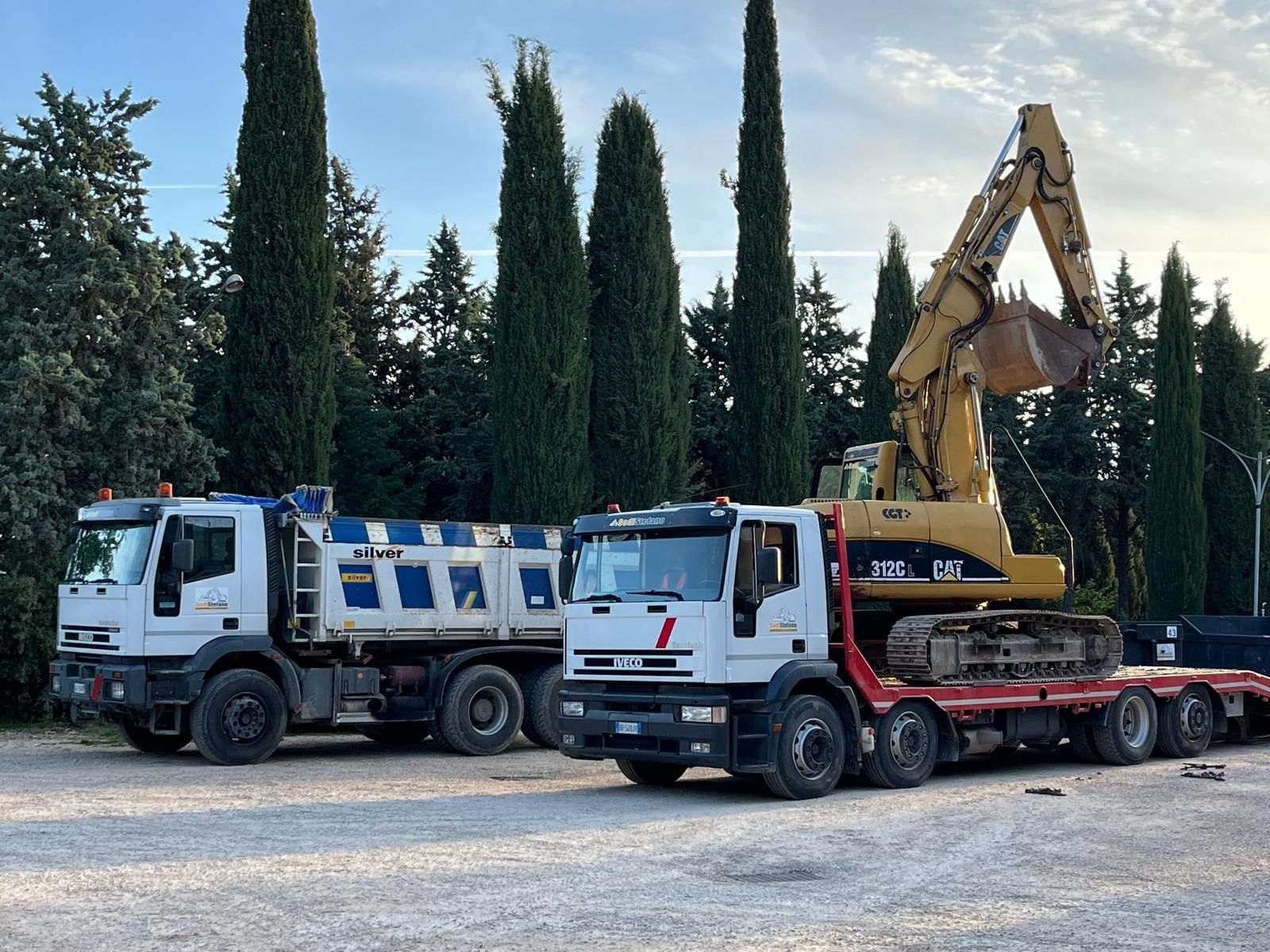Due camion sono parcheggiati uno accanto all'altro in un parcheggio con alberi sullo sfondo.
