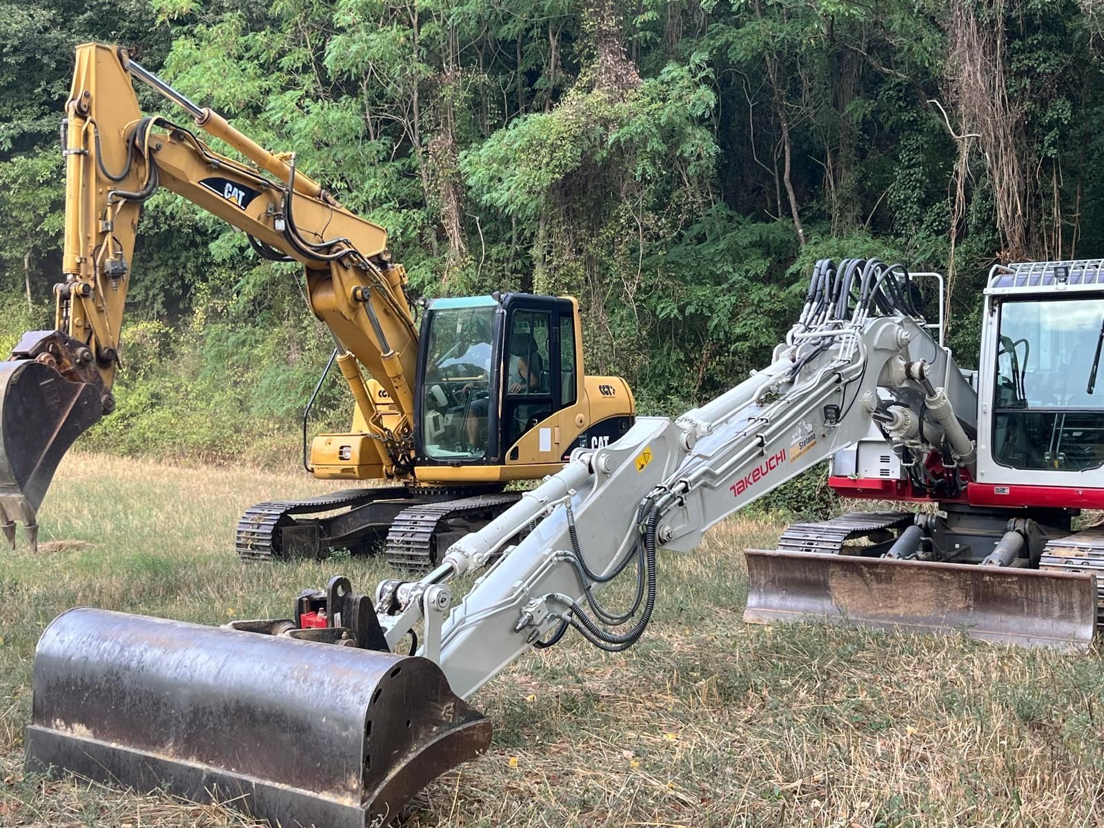 Due escavatori sono parcheggiati uno accanto all'altro in un campo.