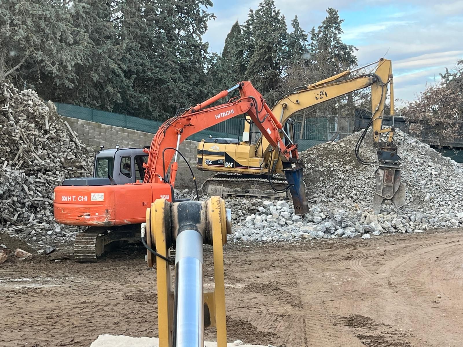 Un paio di escavatori sono seduti in cima a un mucchio di rocce.
