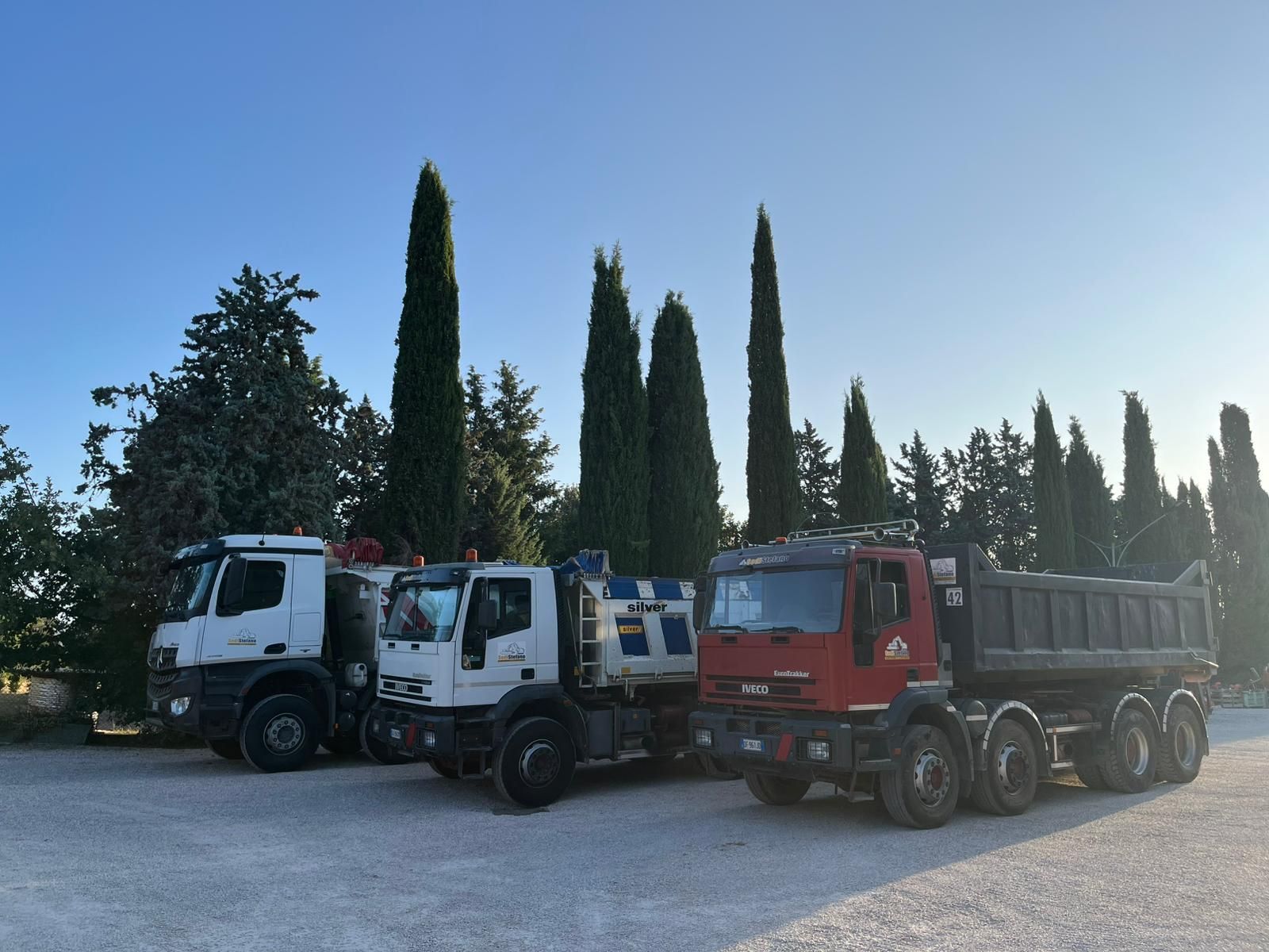 Tre camion sono parcheggiati uno accanto all'altro su una strada sterrata