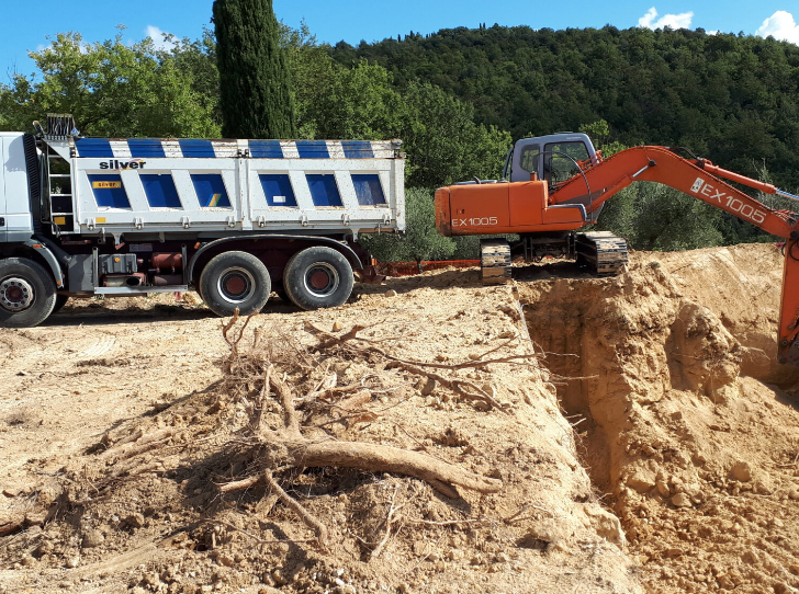 Un autocarro con cassone ribaltabile viene trainato da un escavatore.