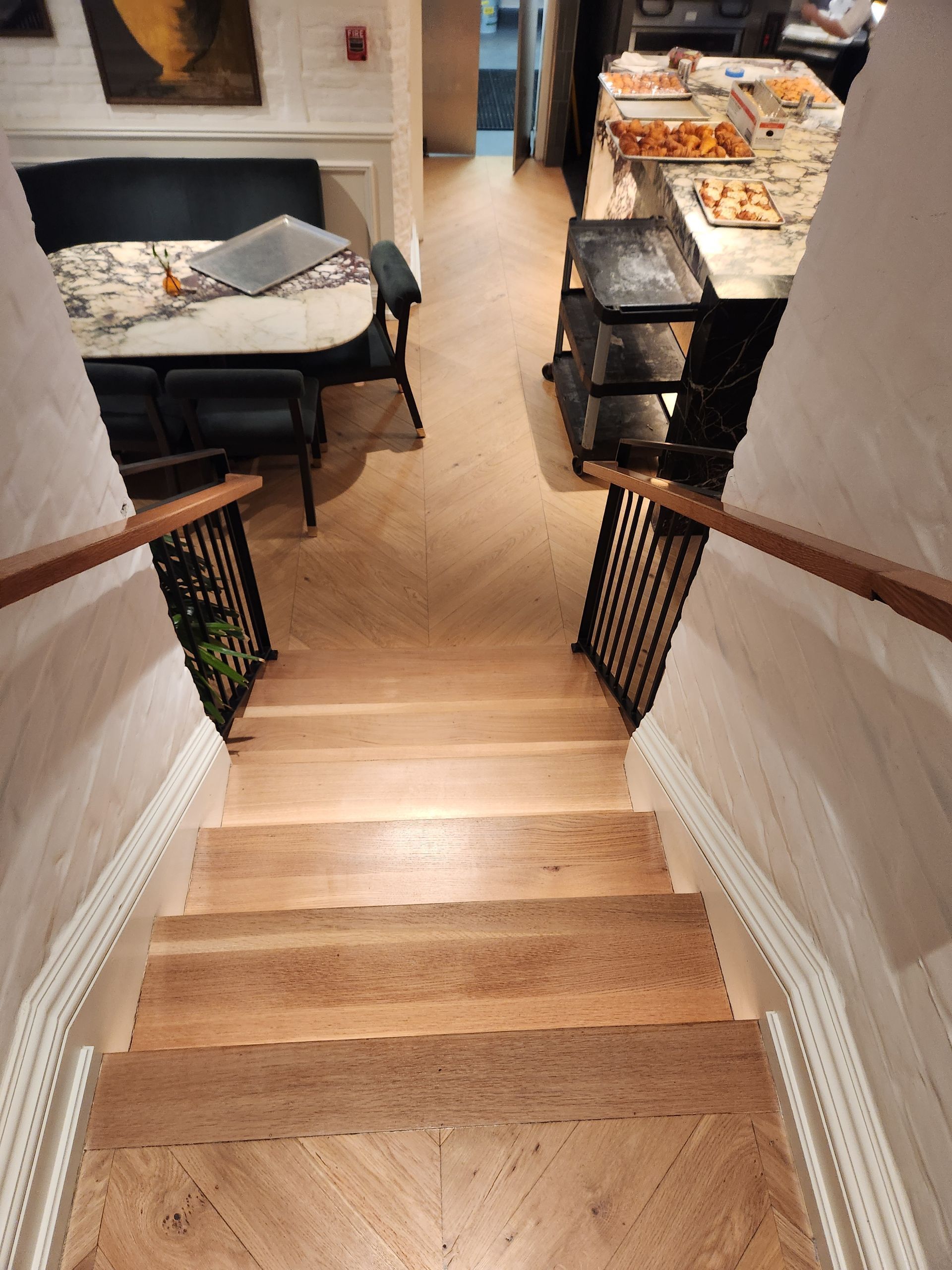 Staircase leading down to a dining area with a table and chairs, warm indoor lighting.