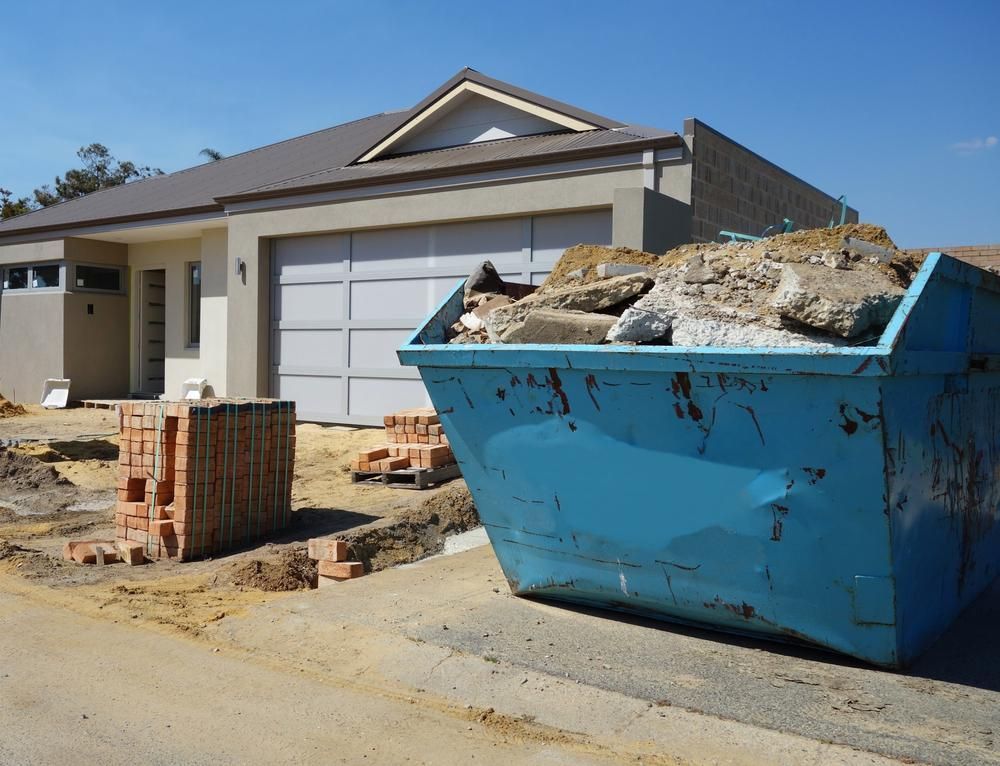 A Blue Dumpster is Sitting in Front of a House — Demco in Currumbin Waters, QLD