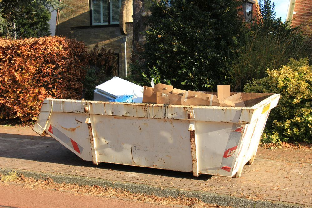 A White Dumpster Filled With Cardboard Boxes is Parked on the Side of the Road — Demco In Currumbin Waters, QLD