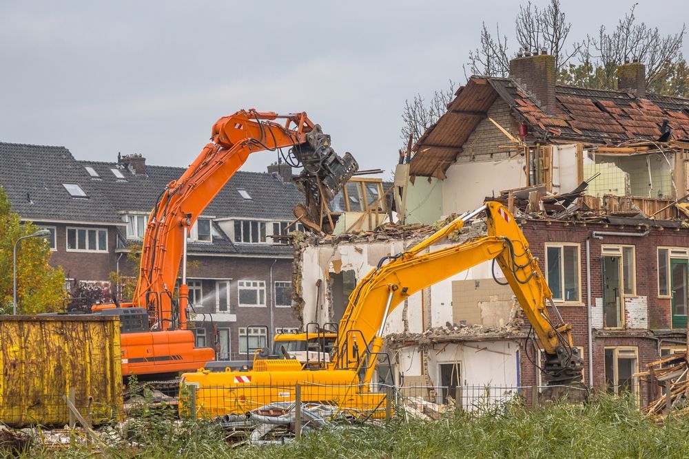Two Yellow Excavators Are Demolishing a Brick Building — Demco In Tweed Shire, NSW
