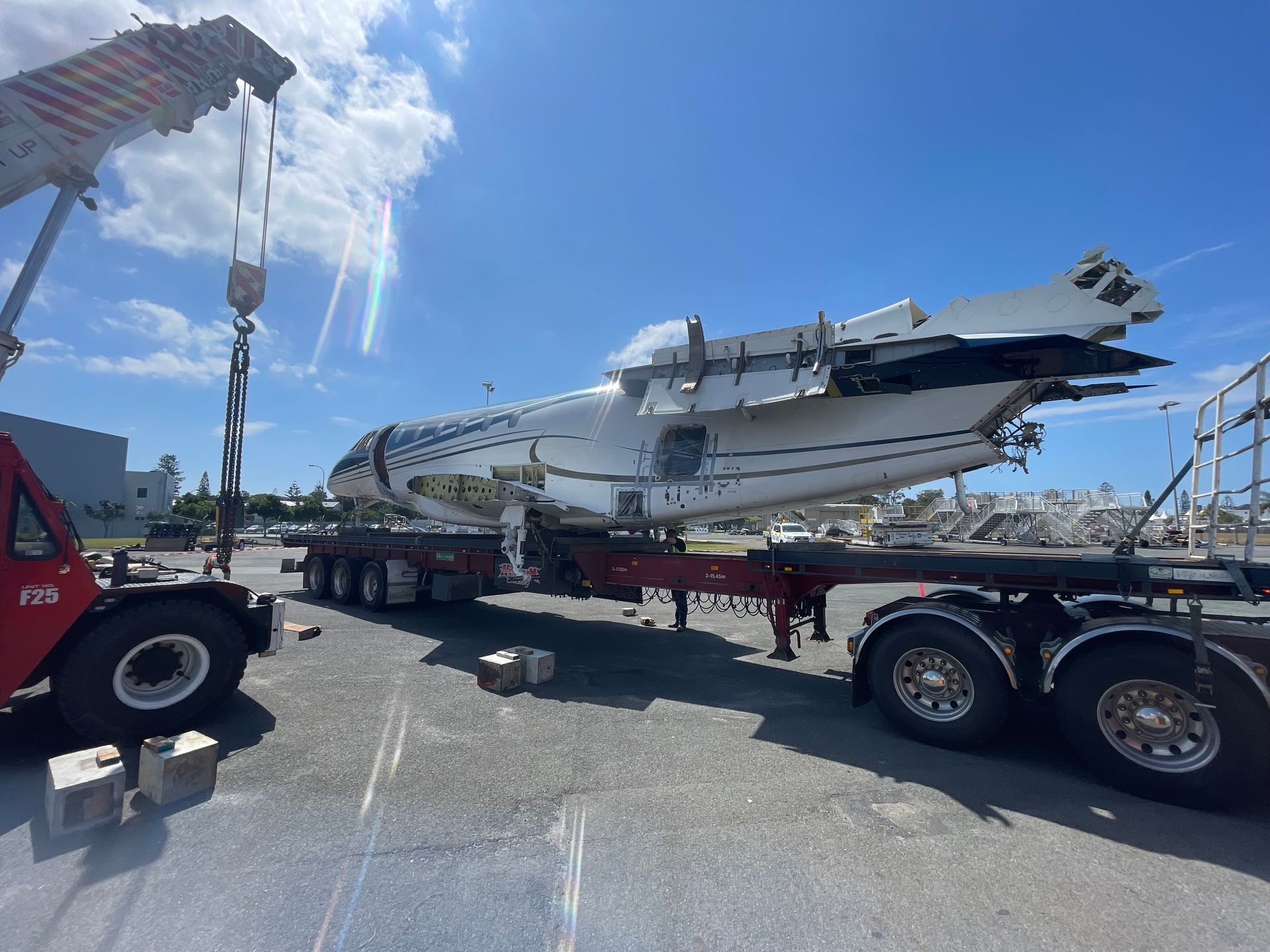 A large airplane is being lifted by a crane on a trailer. — Demco In Currumbin Waters, QLD