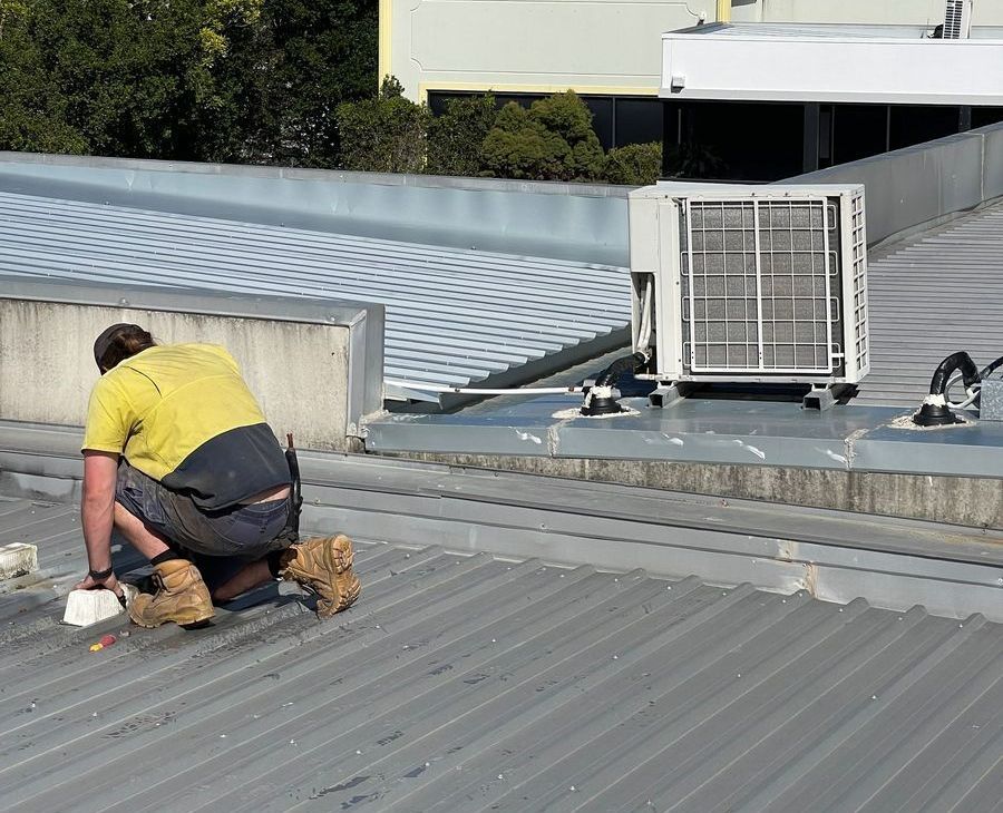 A Man is Kneeling on the Roof of a Building — Demco In Currumbin Waters, QLD