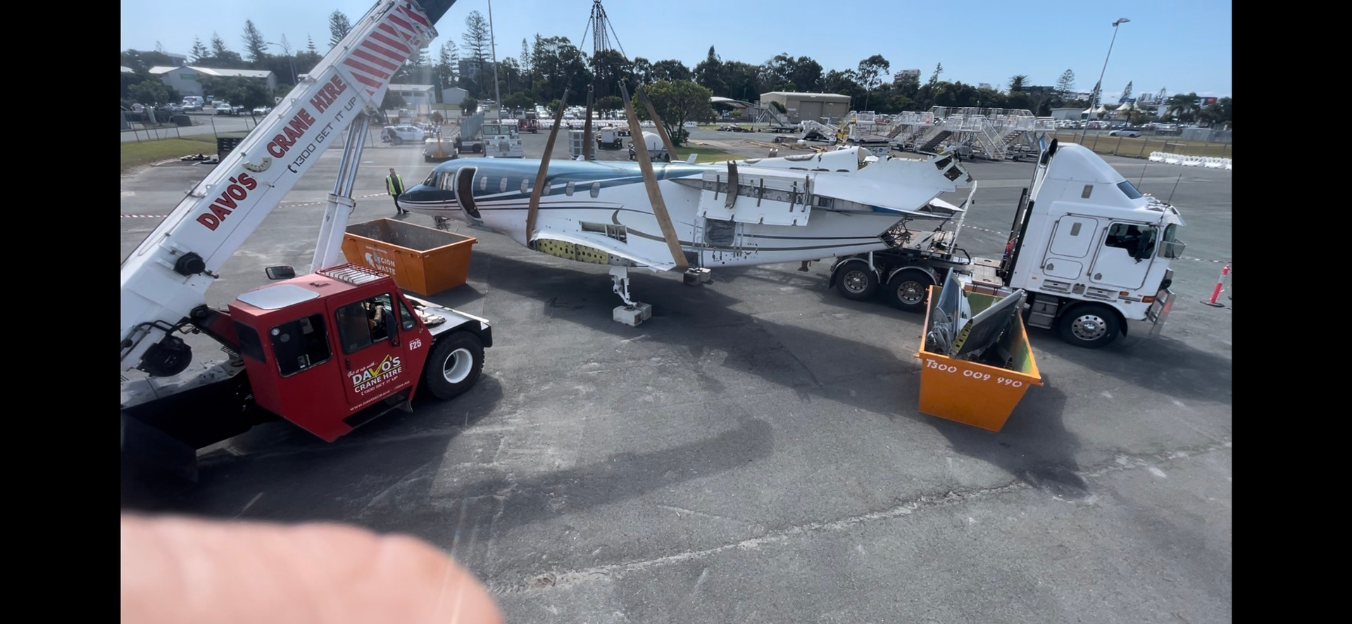 A crane is lifting a plane on a trailer in a parking lot. Demco In Currumbin Waters, QLD