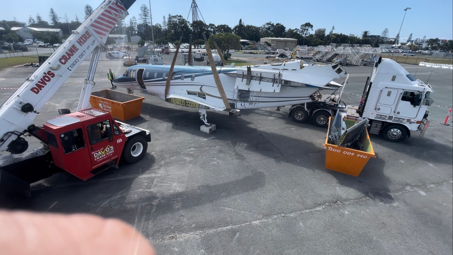 A crane is lifting a plane in a parking lot — Demco in Currumbin Waters, QLD