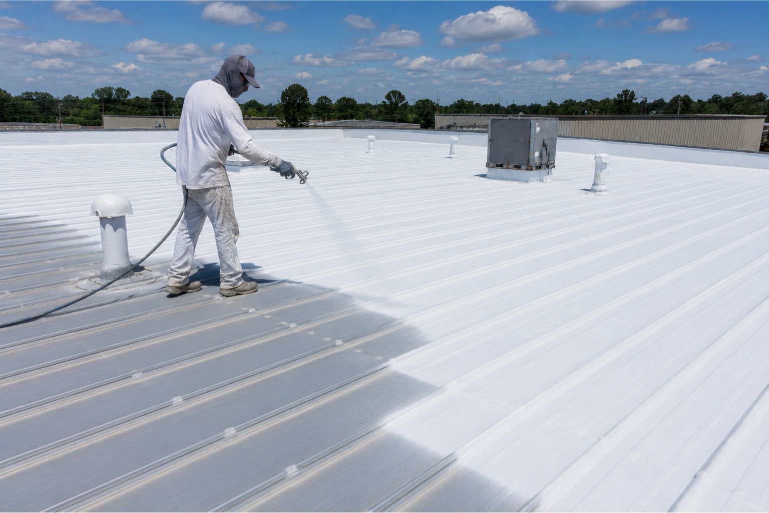 Commercial metal roof being coated with a reflective roof coating system.