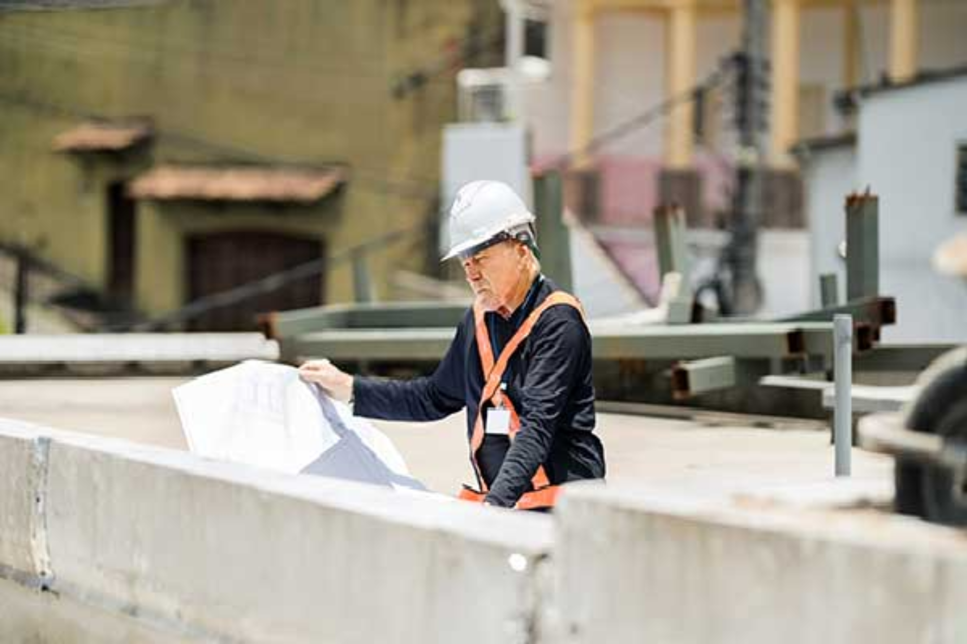A construction worker is looking at a blueprint at a construction site.