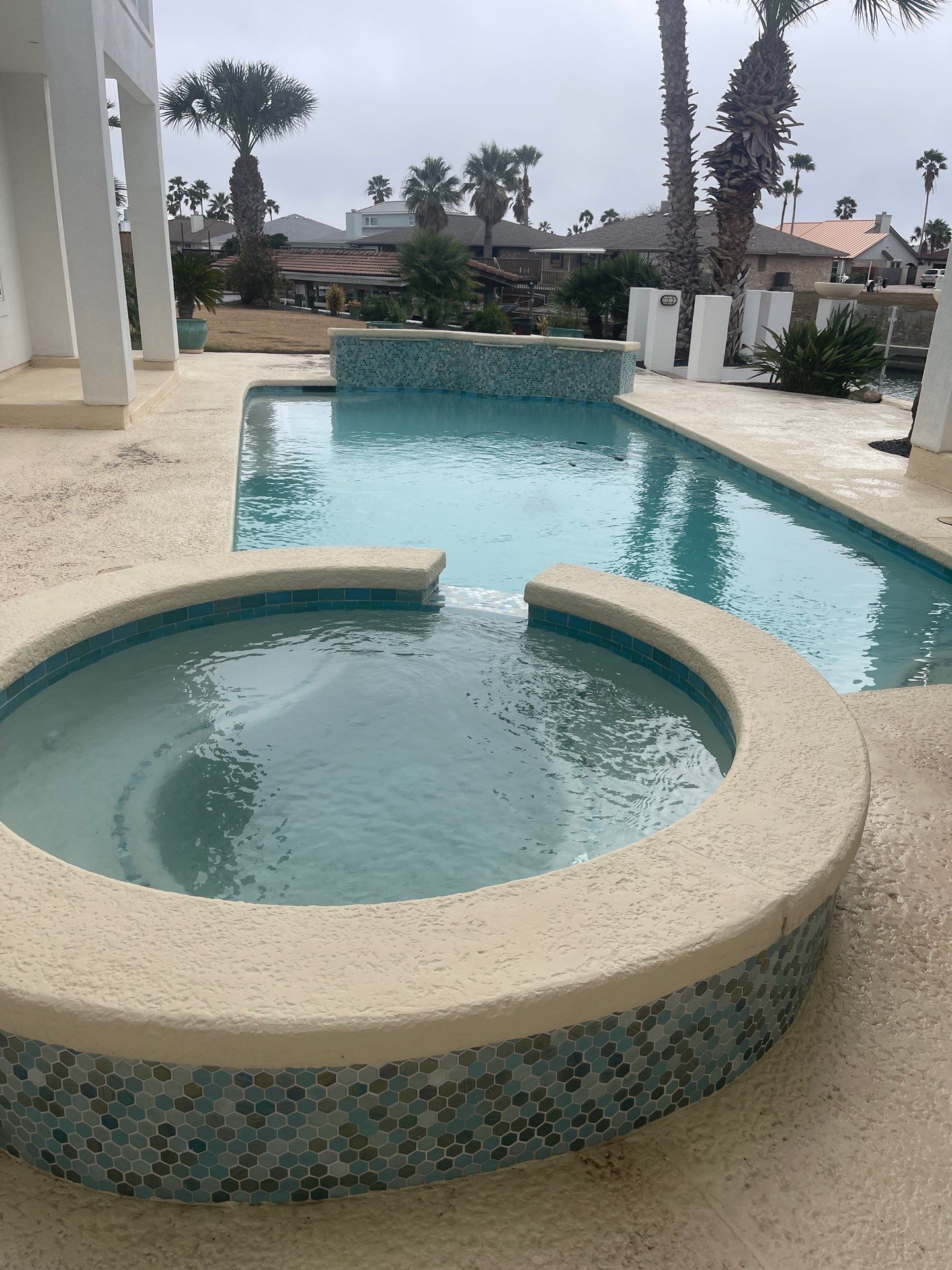 Swimming pool with jacuzzi and water features on a patio.