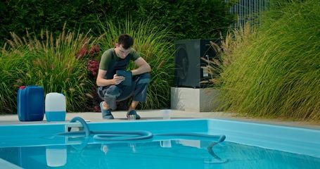 Man checks pool water with bottles and equipment.