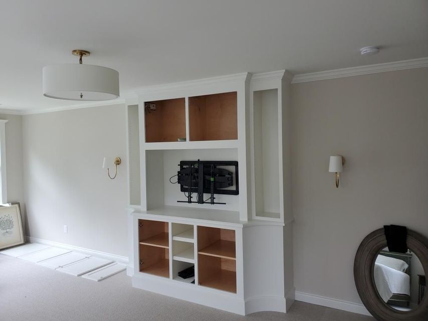 A living room with a built in entertainment center and a flat screen tv mounted on the wall.