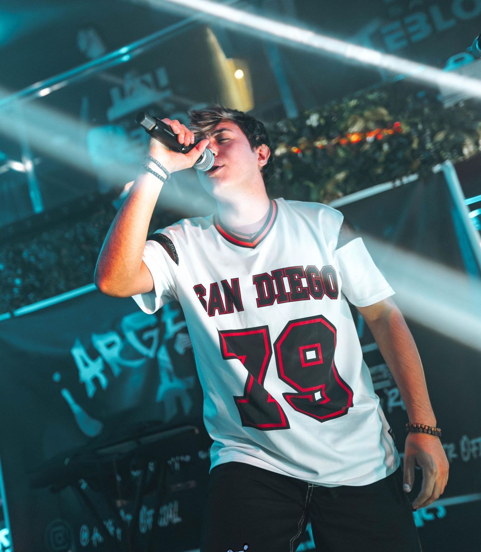 Un hombre cantando en un micrófono con una camiseta de San Diego 79