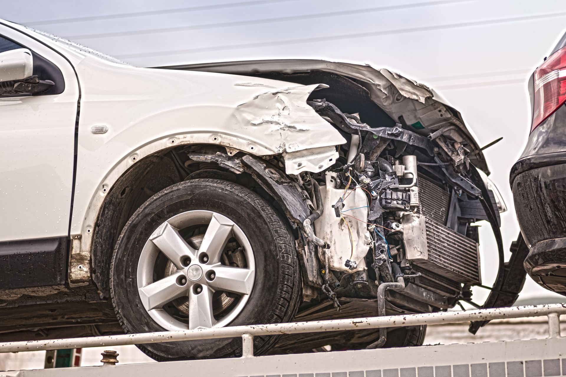 White SUV with severe front-end damage, possibly from a collision, on a tow truck.