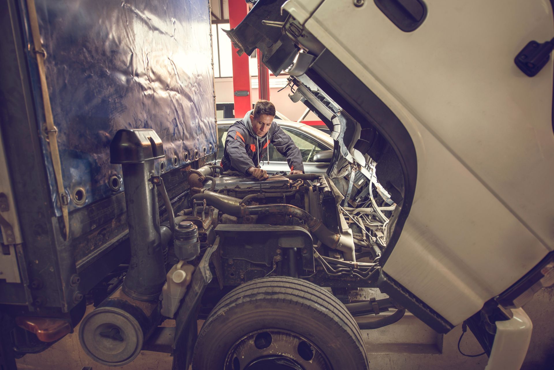Mechanic working on a truck engine in a repair shop.