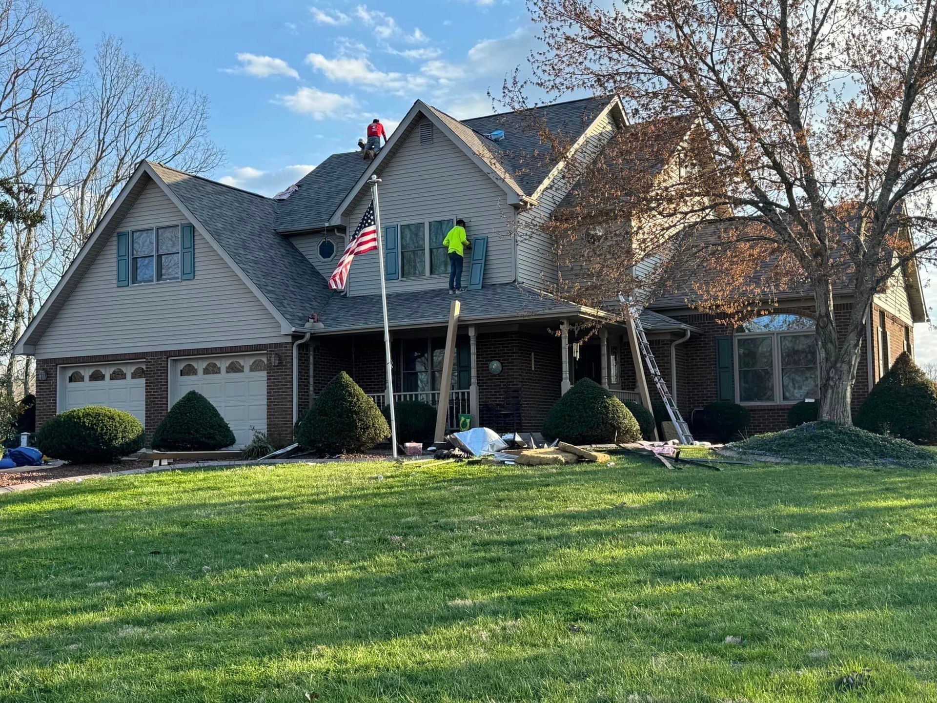 A man is standing on the roof of a large house.