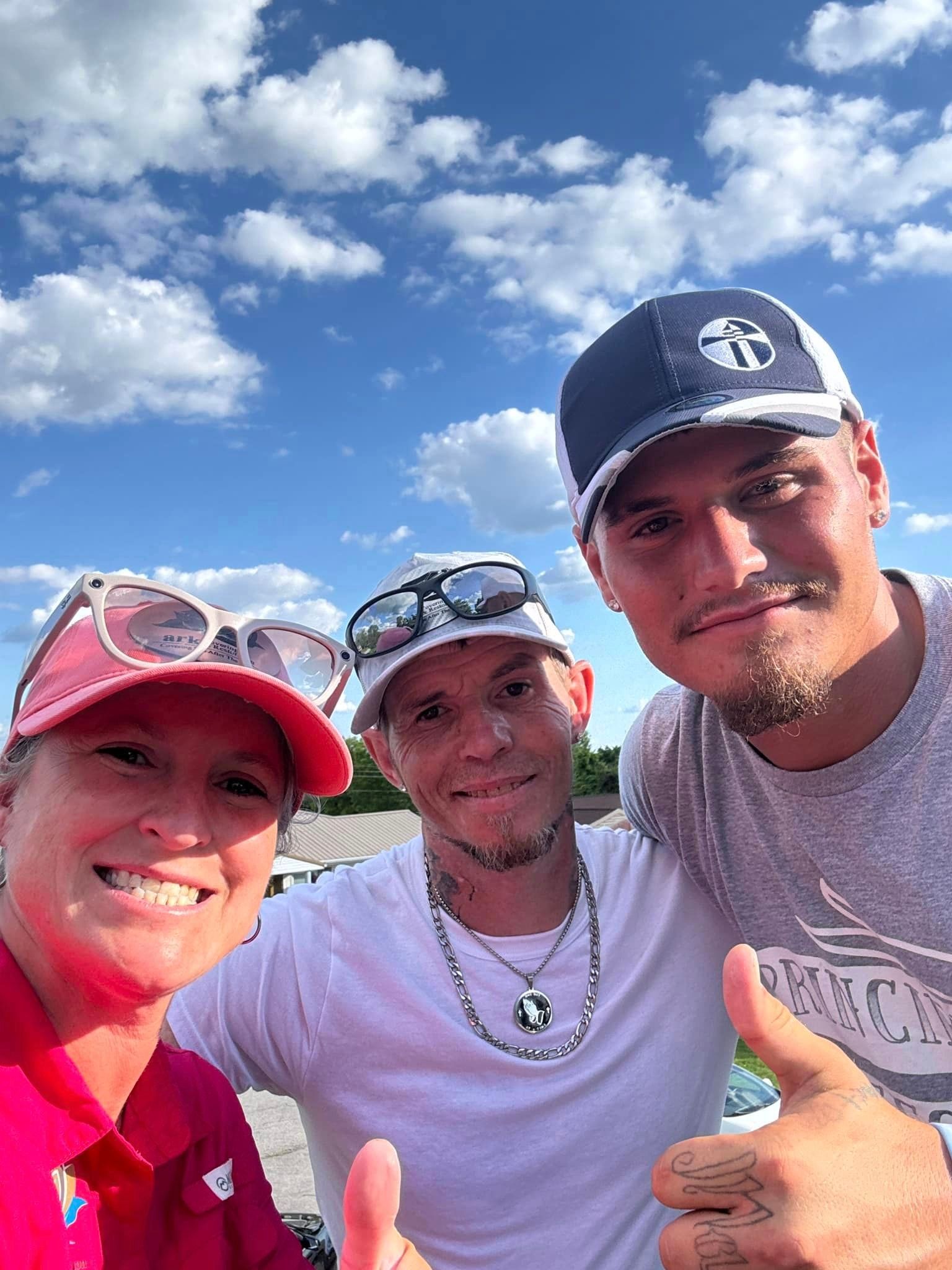 Three people are posing for a picture and one of them is giving a thumbs up.