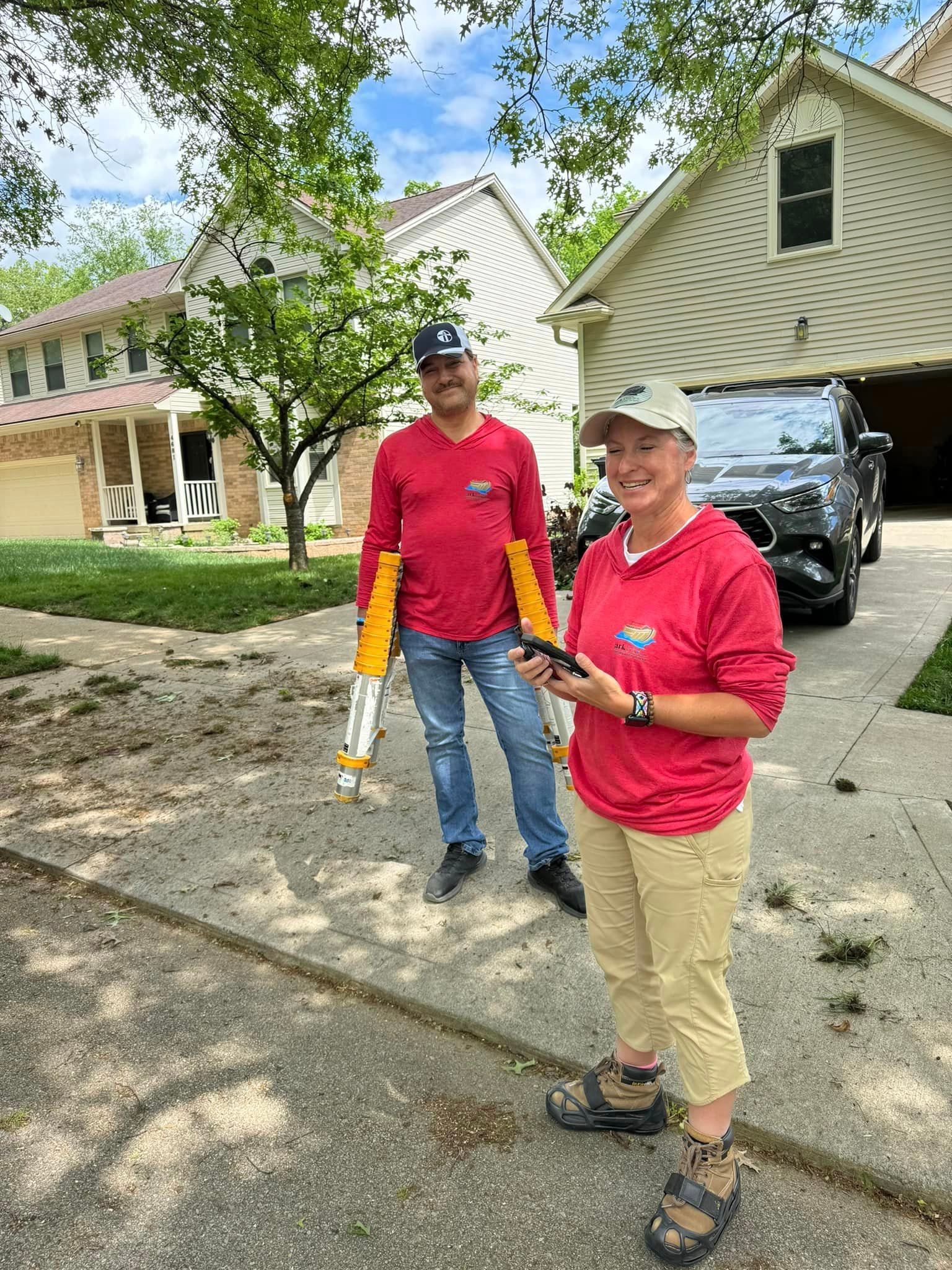 A man and a woman are standing on the sidewalk in front of a house.