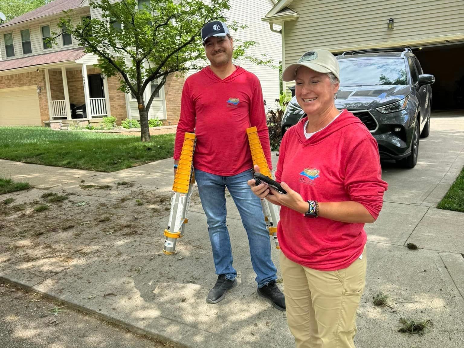 A man and a woman are standing in front of a house.