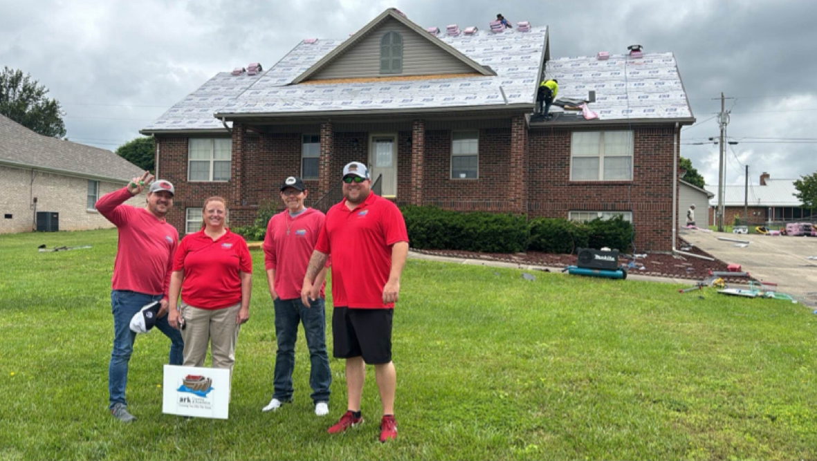 A group of people are standing in front of a house that is being remodeled.