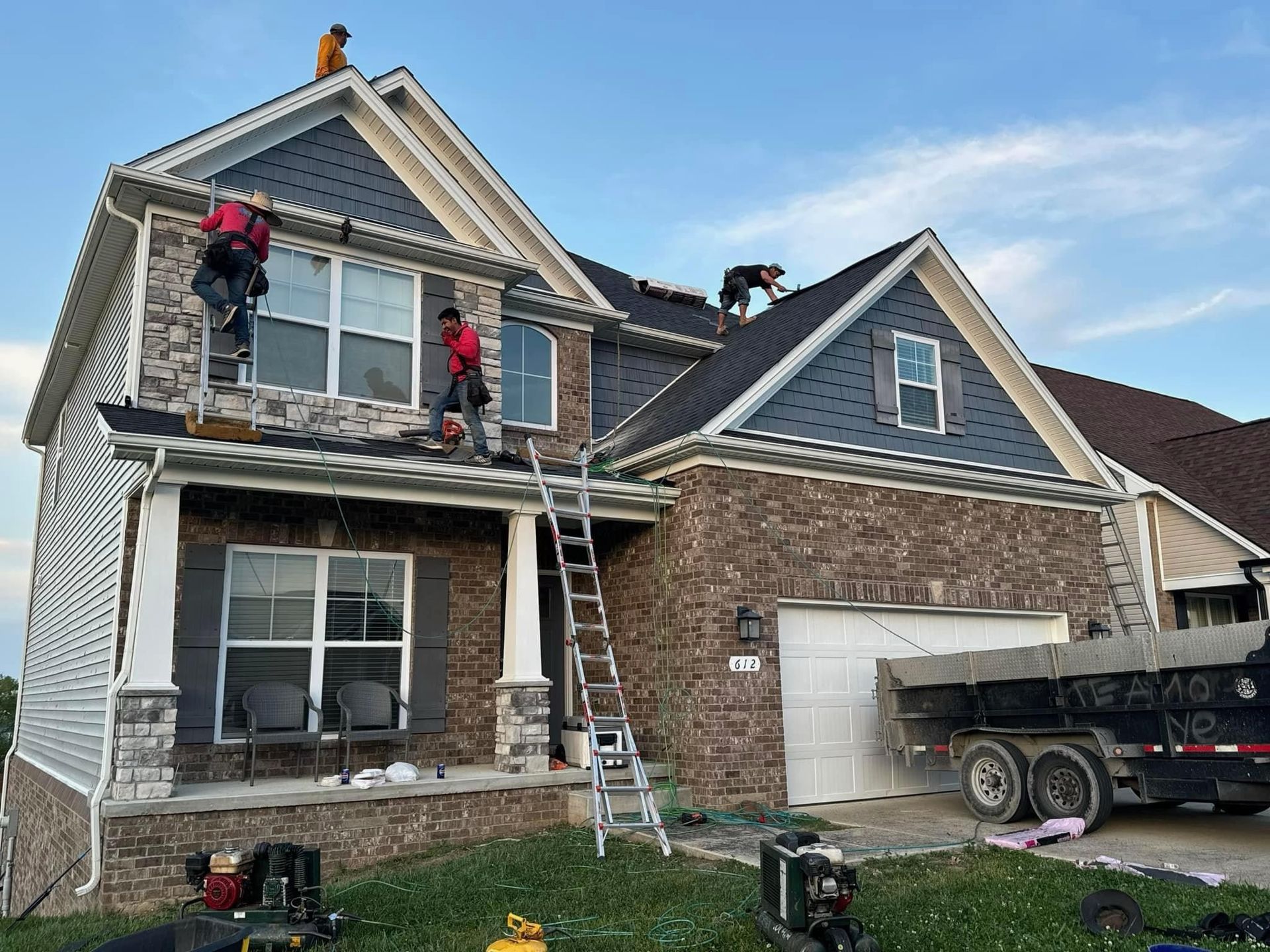 A group of men are working on the roof of a house.