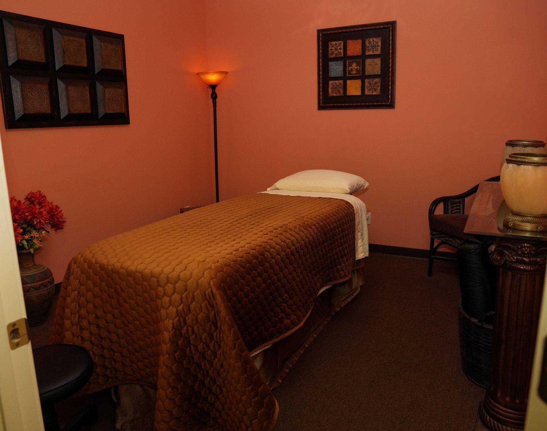 Massage room with a single treatment table, warm lamp, and framed wall art